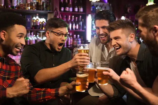 Group of men clinking glasses at a bachelor party in an escape room