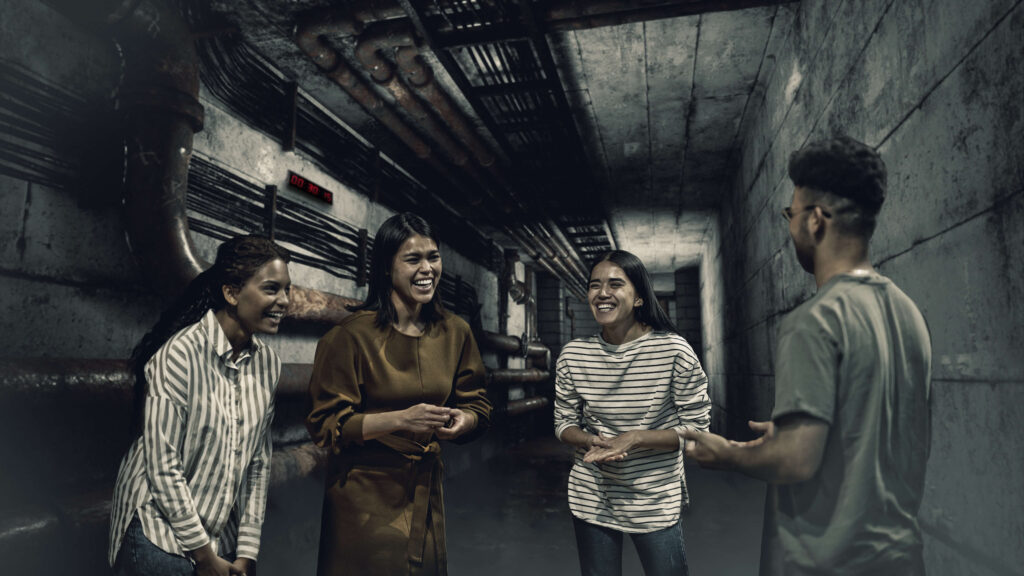 a group of people laughing in a hallway of an escape room